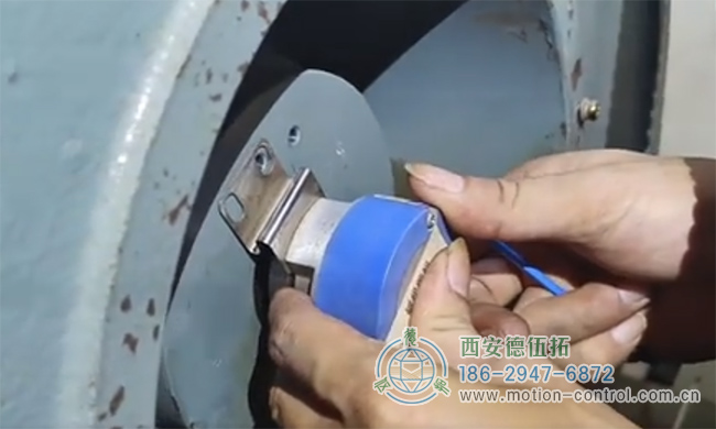 图为工作人员正在对发生飞车现象的电梯编码器进行拆御的照片